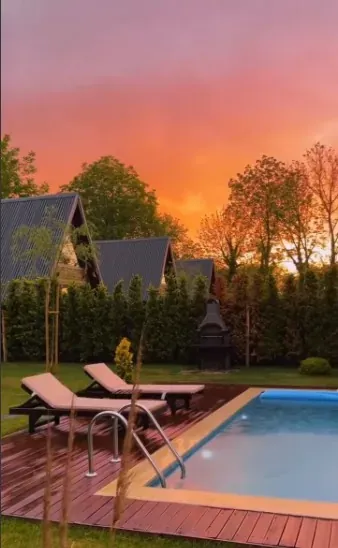 Gün batımında turuncu gökyüzü, A-frame çatılar, çit ve havuz başında şezlonglar
